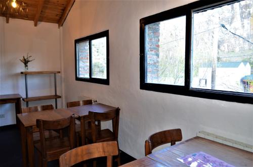 een eetkamer met tafels, stoelen en ramen bij Posada San Antonio in El Chalten