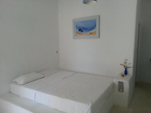 a white bedroom with a bed and a picture on the wall at Anatoli in Ambelas