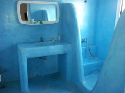 Baño azul con lavabo y espejo en Anatoli, en Ampelas