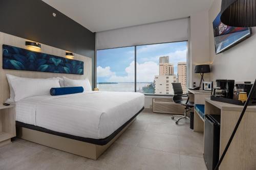 a bedroom with a bed and a desk and a window at River Garden Hotel + Suites in Guayaquil