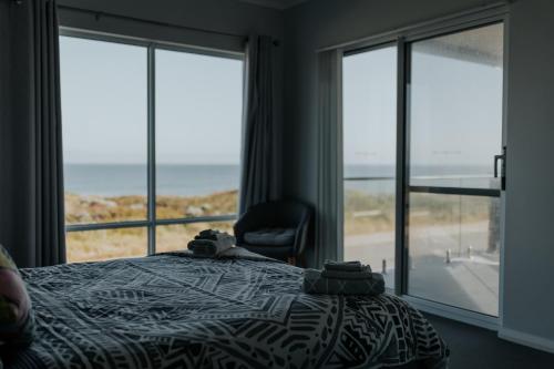 a bedroom with a bed and a chair and windows at Beach House at SeaScapes.. in Mandurah