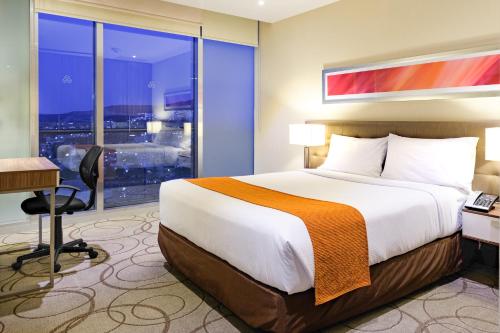 a hotel room with a bed and a desk and a window at The View Hotel by Covalia in San Luis Potosí