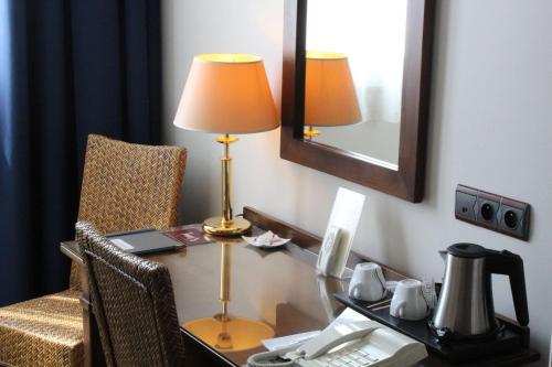 a desk in a hotel room with a lamp and a chair at Best Western de Diane in Nevers