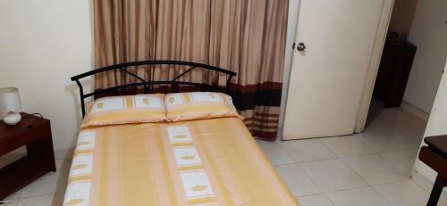 a small bedroom with a bed with yellow and white sheets at cambulos 2 in Cali