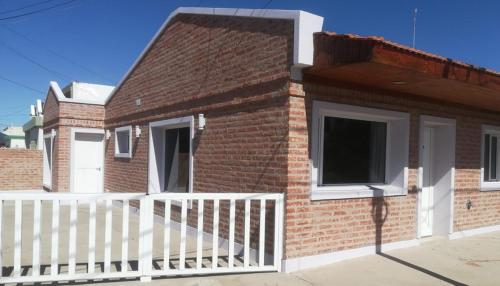 una casa de ladrillo con una valla blanca y un porche en Rufina Alojamiento en Playa Unión
