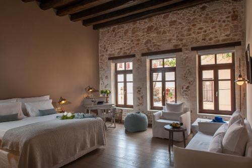 a bedroom with a bed and two chairs and windows at Serenissima Boutique Hotel in Chania