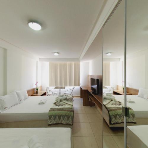 a hotel room with two beds and a television at Flat Mar do Cabo Branco Residence in João Pessoa