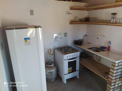 a small kitchen with a stove and a refrigerator at Casa Areiasardin in Barrinha