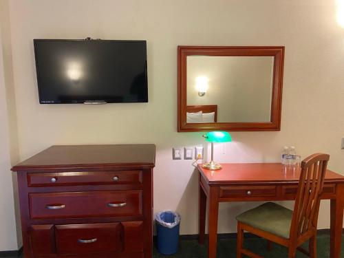 a desk with a dresser and a mirror and a television at Hotel Enterprise Inn Poliforum in León