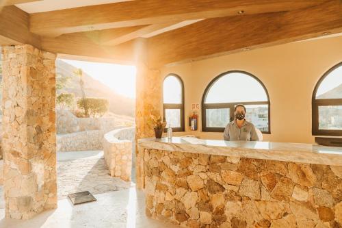 a man standing behind a stone counter in a house at Castillo Blarney Inn in Cabo San Lucas