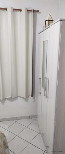 a bathroom with white curtains and a white tiled floor at Férias em Itapema n01 in Itapema