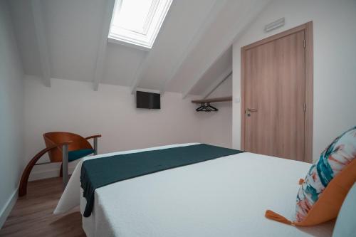 um quarto com uma cama, uma cadeira e uma porta em Harbour49 - AVEIRO FLATS & SUITES em Aveiro