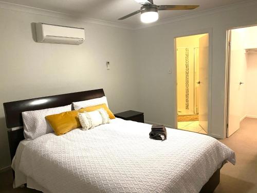 - une chambre avec un lit doté d'oreillers jaunes et d'un ventilateur de plafond dans l'établissement Modern 4BR close to the Airport- Whole house, à Gladstone