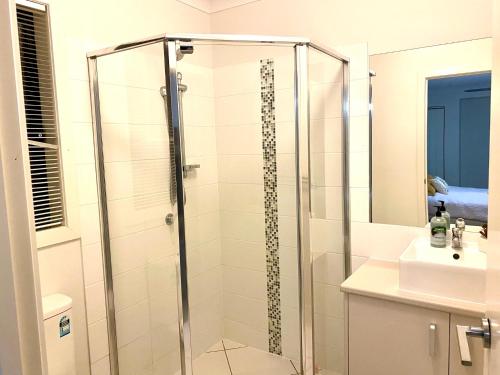 La salle de bains est pourvue d'une douche avec une porte en verre. dans l'établissement Modern 4BR close to the Airport- Whole house, à Gladstone