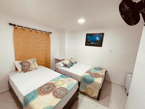a bedroom with two beds and a tv on the wall at Hotel Eterna Primavera in Medellín