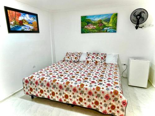 a bedroom with a bed and paintings on the wall at Hotel Eterna Primavera in Medellín