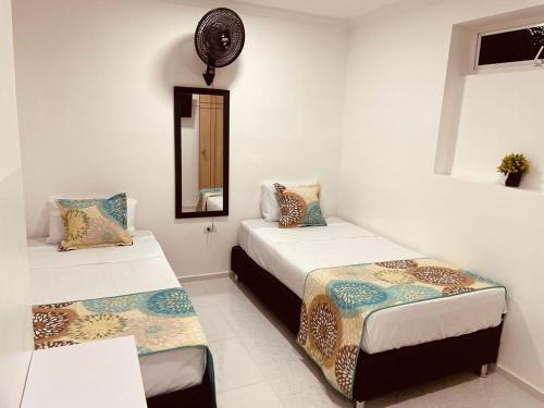 a room with two beds and a mirror at Hotel Eterna Primavera in Medellín