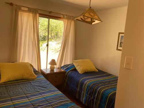 a bedroom with two beds and a window at Cabañas Parador del Aguila - Lago Vichuquén in Vichuquén