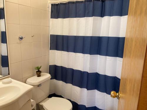 a bathroom with a toilet and a blue and white shower curtain at Cabañas Parador del Aguila - Lago Vichuquén in Vichuquén