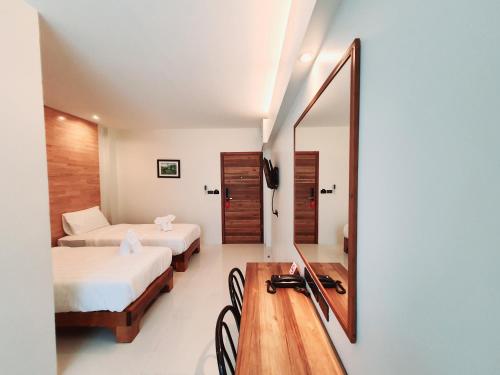 a room with two beds and a desk with a mirror at SUhotel Suratthani in Surat Thani