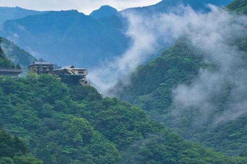 a misty mountain with a house on top of it at Iya Onsen in Miyoshi
