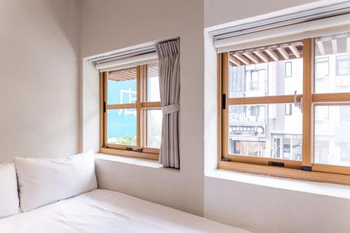 a bedroom with a bed and two windows at Tiin Tinn Inn - Tiehua Xiutai in Taitung City