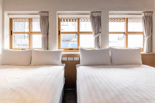 two beds in a room with two windows at Tiin Tinn Inn - Tiehua Xiutai in Taitung City