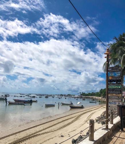 a beach with boats in the water and a palm tree at Tapirandú Pousada in Morro de São Paulo
