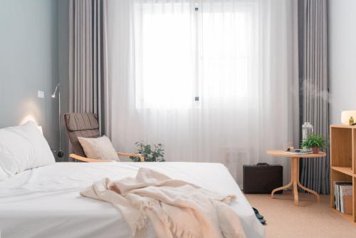 台東市にあるTaitung mini trip hostelのベッドルーム1室(白いベッド1台、椅子、窓付)