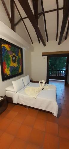 a white bed in a room with a painting on the wall at Hotel Restaurante Sion in Moniquirá
