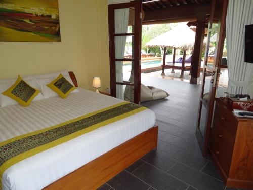 a bedroom with a bed and a television and a pool at Bale Solah Lombok Holiday Resort in Senggigi 