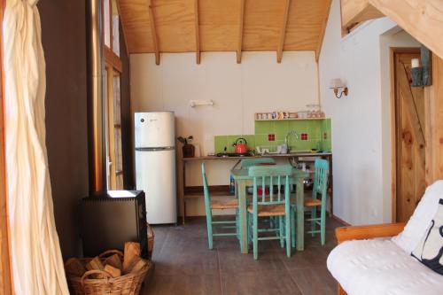 a kitchen with a table and chairs and a refrigerator at Cabaña Los Carpinteros, Conguillïo, Sector Los Paraguas in Vilcún