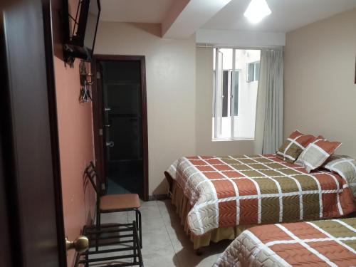 a hotel room with two beds and a window at Hostal EL CALLEJÓN in Ibarra