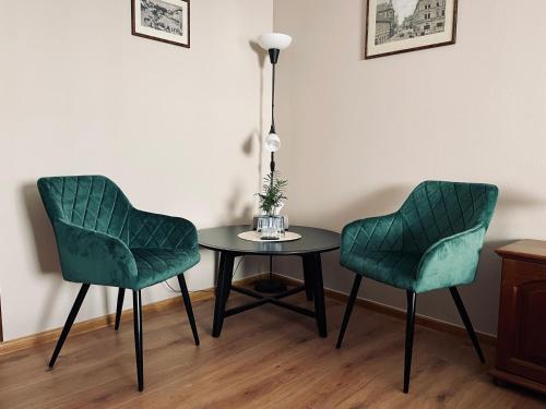 two green chairs and a table with a lamp at Pension Silvie in Vlašim