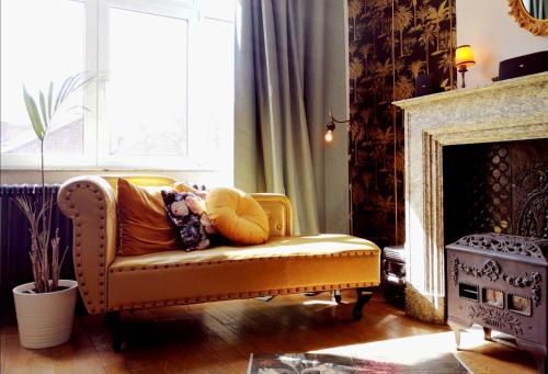 a yellow couch in a living room with a fireplace at Retro Parisian Apartment - Spacious 75m2 and fully equipped - Fabulous location IN city center in Namur
