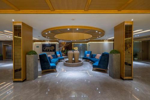 a lobby with blue chairs and a circular ceiling at Sarovar Portico Morbi in Morbi