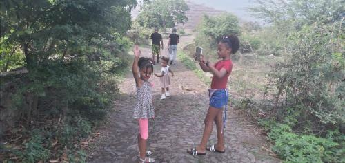 three children standing on a path with their hands in the air at Ciza e Rose in Portela