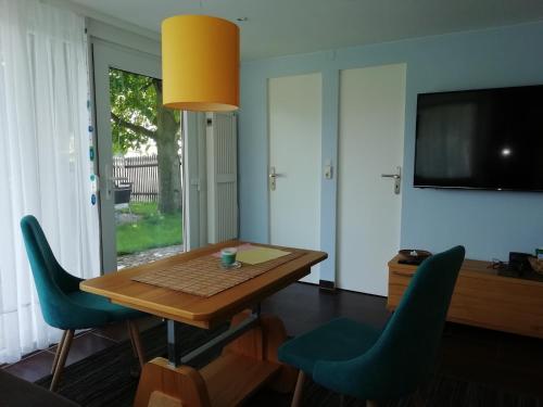 a dining room with a wooden table and blue chairs at Kleiner Bungalow im Grünen in Radeberg