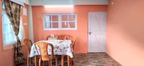 uma sala de jantar com uma mesa e cadeiras e uma porta branca em Pema lhamu homestay em Darjeeling