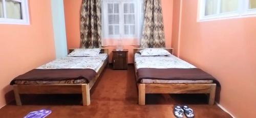 2 camas en una habitación con ventana en Pema lhamu homestay en Darjeeling