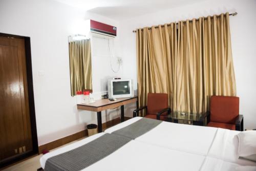 a bedroom with a bed and a desk with a television at Hotel Tanish in Madgaon