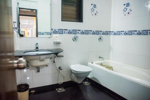 a bathroom with a toilet and a sink and a bath tub at Hotel Tanish in Madgaon