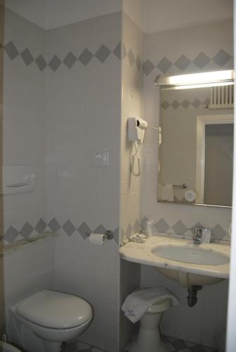 a bathroom with a sink and a toilet and a mirror at Hotel Carlton in Riccione