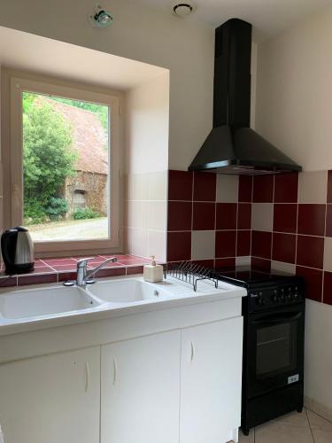 une cuisine avec un évier, une cuisinière et une fenêtre dans l'établissement Maison chaleureuse à la campagne, à Payrignac