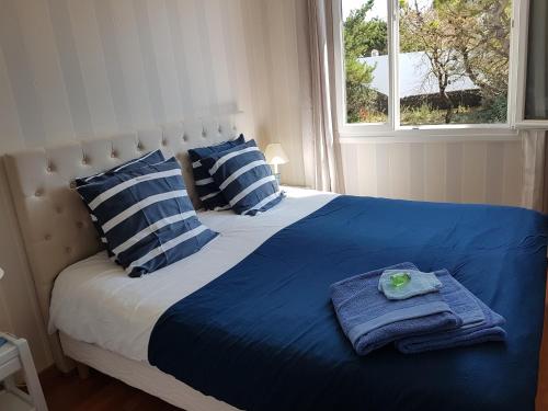 Una cama con almohadas azules y blancas y toallas. en "Maison de la mer" à 200 m de la plage - St Jean de Monts en Saint-Jean-de-Monts