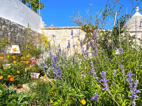 a garden with purple flowers in front of a brick wall at Trullo Aprìco in Alberobello