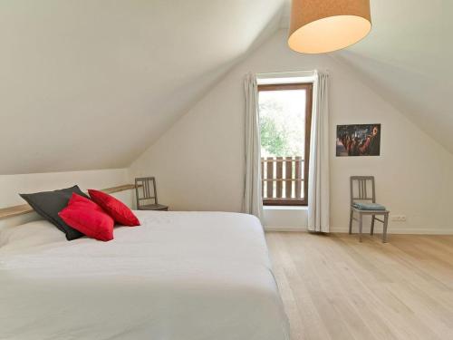 哈穆瓦爾的住宿－Ecologis Hamoir，一间卧室配有一张带红色枕头的床和一扇窗户