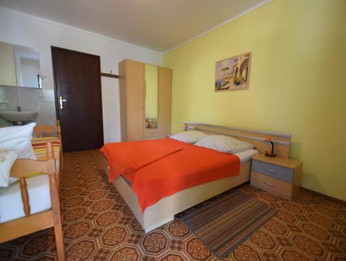 a bedroom with a bed with a orange comforter at Apartments Skender in Vantačići
