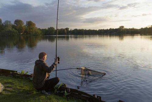 a man holding a fishing pole in a lake at Breitner Chalet op de Schatberg in Sevenum