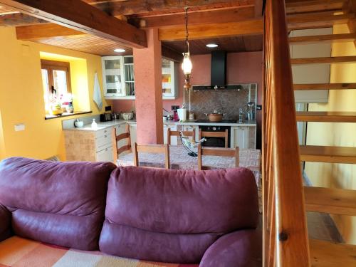 Una sala de estar con un sofá morado y una cocina. en Cal Rafalet, en Ger